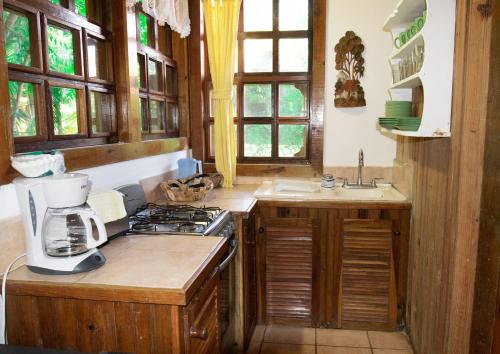 a kitchen with wooden cabinets and a stove top oven at Hotel Posada Arco Iris in Roatán