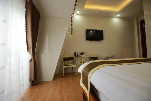 a bedroom with a bed and a table and a tv at VES - PA Luxury Hotel in Da Lat