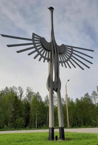 a statue of a bird standing in the grass at Villa Karhunkehto in Luosto