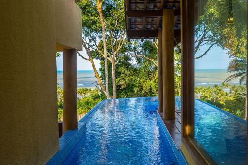 a swimming pool in a house with a view of the ocean at Charm Bahia Residencias in Arraial d'Ajuda