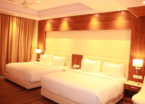 two beds in a hotel room with white sheets at Sarovar Portico, Somnath in Somnath