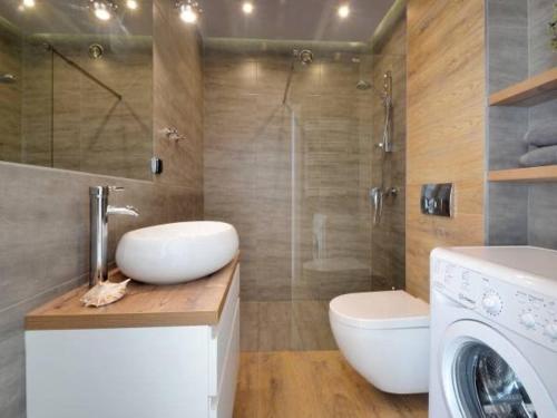 ein Badezimmer mit einem Waschbecken und einer Waschmaschine in der Unterkunft Apartament Biały in Władysławowo