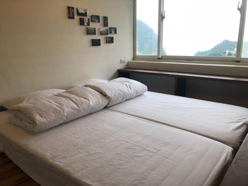 a bed in a room with a large window at Jiufen Gourd Stone TreeHouse 137 in Ruifang