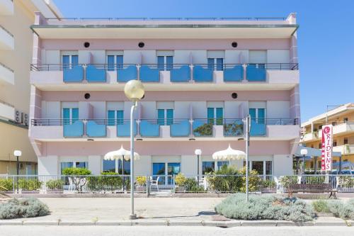 a large pink building with blue balconies at Hotel Ridens in Rimini
