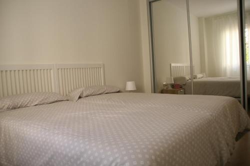 a bedroom with a large white bed with a mirror at Apartamentos Apartour Bormujos in Bormujos