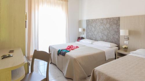 Cette chambre comprend 2 lits et une fenêtre. dans l'établissement Hotel Ridens, à Rimini