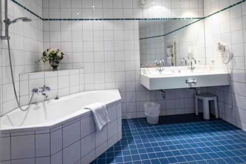 ザルツブルクにあるアパートメント ホテル シャッフェンラーツの白いタイル張りのバスルーム(バスタブ、シンク付)