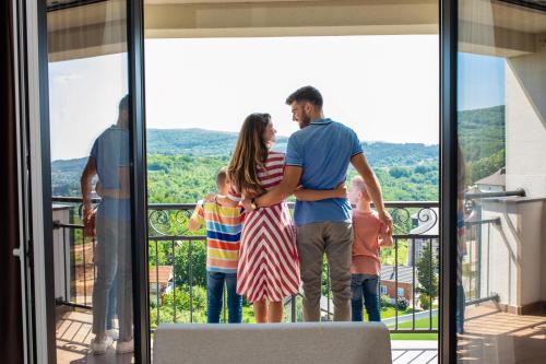 a family standing on the balcony of a house at Movenpick Resort and Spa Fruske Terme in Vrdnik