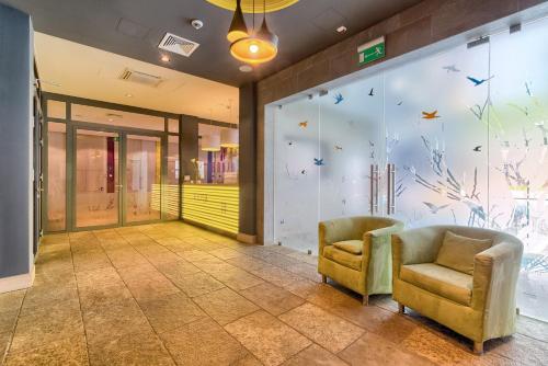 a lobby with two chairs and a wall with birds on it at Hanza Pałac Wellness & SPA in Warlubie