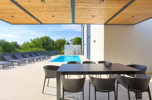 a patio with a table and chairs and a pool at Casa Bela in Klimno