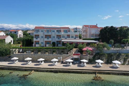 a group of tables and umbrellas next to the water at Pension Augustino in Ražanac