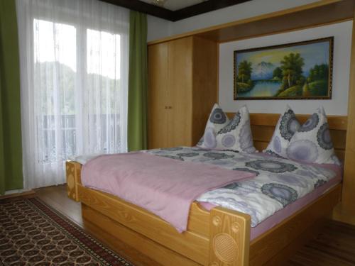 1 dormitorio con cama grande de madera y ventana en Gästehaus am Walde - Familie Troller, en Ledenitzen