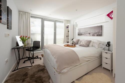 una camera bianca con un grande letto e una scrivania di Fistral beach Penthouse, Newquay a Crantock