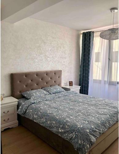 a bedroom with a bed with a blue comforter and a window at Apartment Luxury in Râmnicu Vâlcea