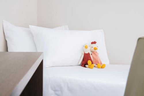 two stuffed penguins sitting on a white bed at Waterfront in Sliema