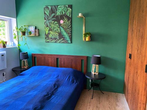 Un dormitorio con una cama azul y paredes verdes en Vuko Vendégház, en Balatonboglár