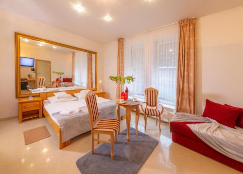 1 dormitorio con cama, mesa y espejo en Murena Hotel i Restauracja, en Ustronie Morskie