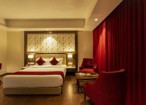 a hotel room with a bed and a red curtain at Sarovar Portico, Somnath in Somnath