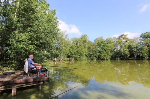a man sitting on a dock fishing on a lake at Camping Baalse Hei in Turnhout