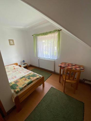 a bedroom with a bed and a table and a window at Agroturystyka Marysieńka in Rymanów-Zdrój