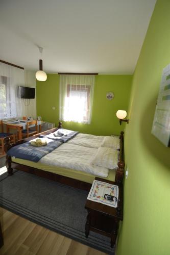 Un dormitorio con una cama con paredes verdes y una mesa. en Guest House Žnidar, en Bohinj