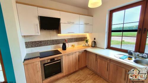 a kitchen with white cabinets and a large window at Agrosielanka in Lipnica