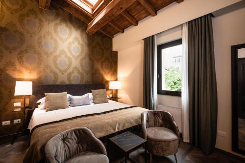 a bedroom with a bed with two chairs and a window at Corte Guelfa in Florence