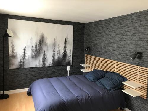 une chambre avec un lit avec un tableau sur le mur dans l'établissement Les Appartements de St-Etienne, à Fécamp