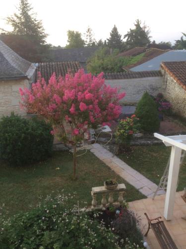 un pequeño árbol con flores rosas en un patio en La Tour de Gué en Mirebeau