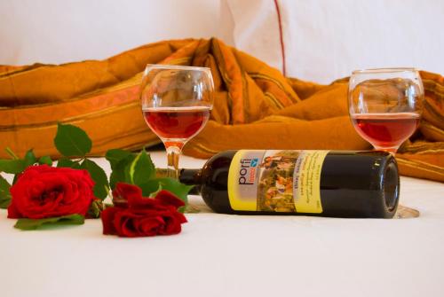 two glasses of wine and a bottle and roses at Porfi Beach Hotel in Nikiti