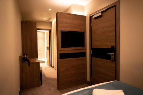a room with a door open and a television mounted on the wall at Oxford Hotel in London
