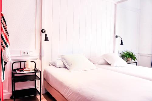 two beds in a room with white walls at Hotel & Restaurant Marina Palamós in Palamós