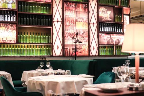 a restaurant with white tables and green chairs and wine bottles at Hotel & Restaurant Marina Palamós in Palamós