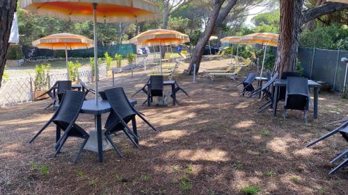 a group of tables and chairs with umbrellas at Hotel Paradiso Verde in Marina di Bibbona