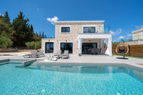 a villa with a swimming pool in front of a house at Diosas Luxury Villas in Pilaroú