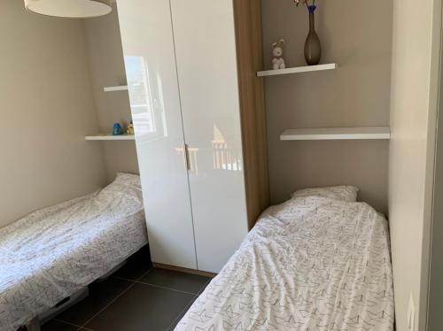 a small bedroom with two beds and a closet at Karthuizer appartement in Nieuwpoort