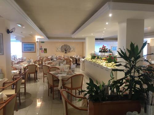 a dining room with tables and chairs and plants at Hotel Conca Verde in Lignano Sabbiadoro