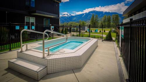 a hot tub in a patio with mountains in the background at Stoke Hotel SureStay Collection by Best Western in Revelstoke