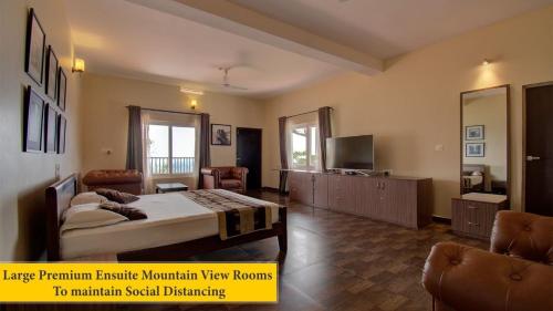 a bedroom with a bed and a television and two chairs at Forestdale Coorg in Virajpet