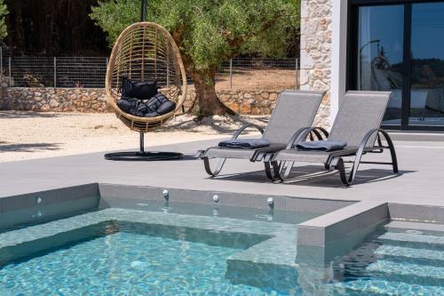 two chairs sitting next to a swimming pool at Diosas Luxury Villas in Pilaroú