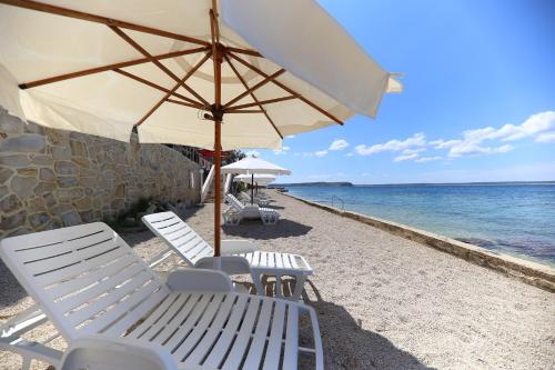 a group of chairs and an umbrella on the beach at Pension Augustino in Ražanac