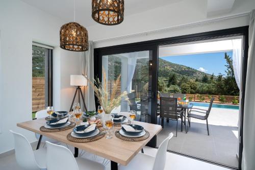 a dining room with a table and chairs and a pool at Diosas Luxury Villas in Pilaroú