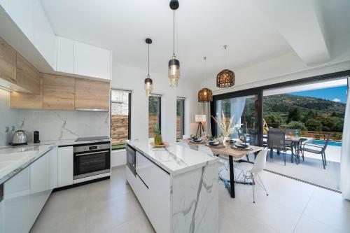 a kitchen with white appliances and a dining room with a table at Diosas Luxury Villas in Pilaroú