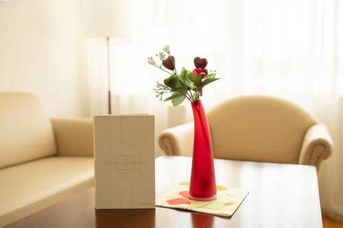 a red vase with flowers sitting on a table at Hotel-Restaurant Liebnitzmühle in Raabs an der Thaya