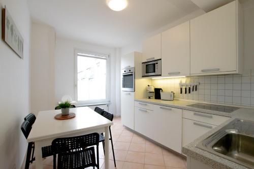 una cocina con armarios blancos y una mesa pequeña con sillas. en Old Town 2 Room Apartments, en Düsseldorf