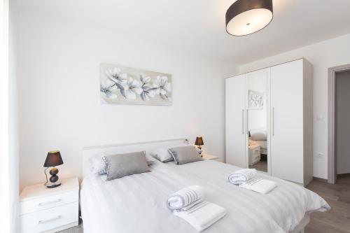 een witte slaapkamer met een wit bed en een spiegel bij zdenka in Rabac