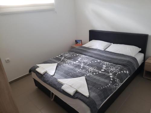 ein Bett mit einer schwarzen und weißen Decke und Kissen in der Unterkunft Apartmani Pajic in Jagodina