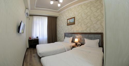 a hotel room with two beds with white sheets at ARK BILLUR HALAL Hotel in Tashkent