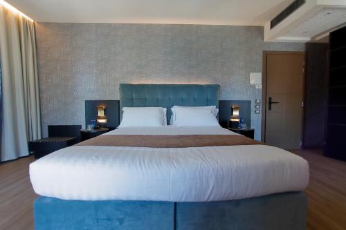 a large bed in a hotel room with two lamps at Hotel Bell'arrivo by Dori in Peschiera del Garda