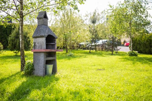 a stone bird house sitting in a field of grass at Domki nad stawem. in Polańczyk